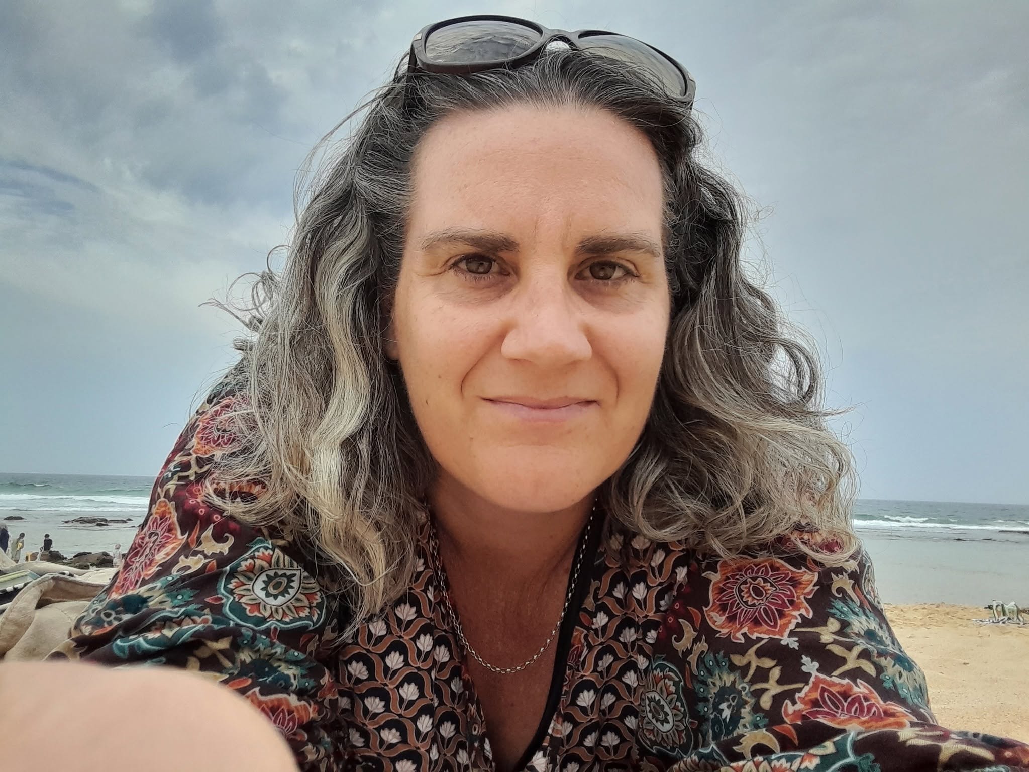 Claire Allison outdoors at the beach, sky and water behind her