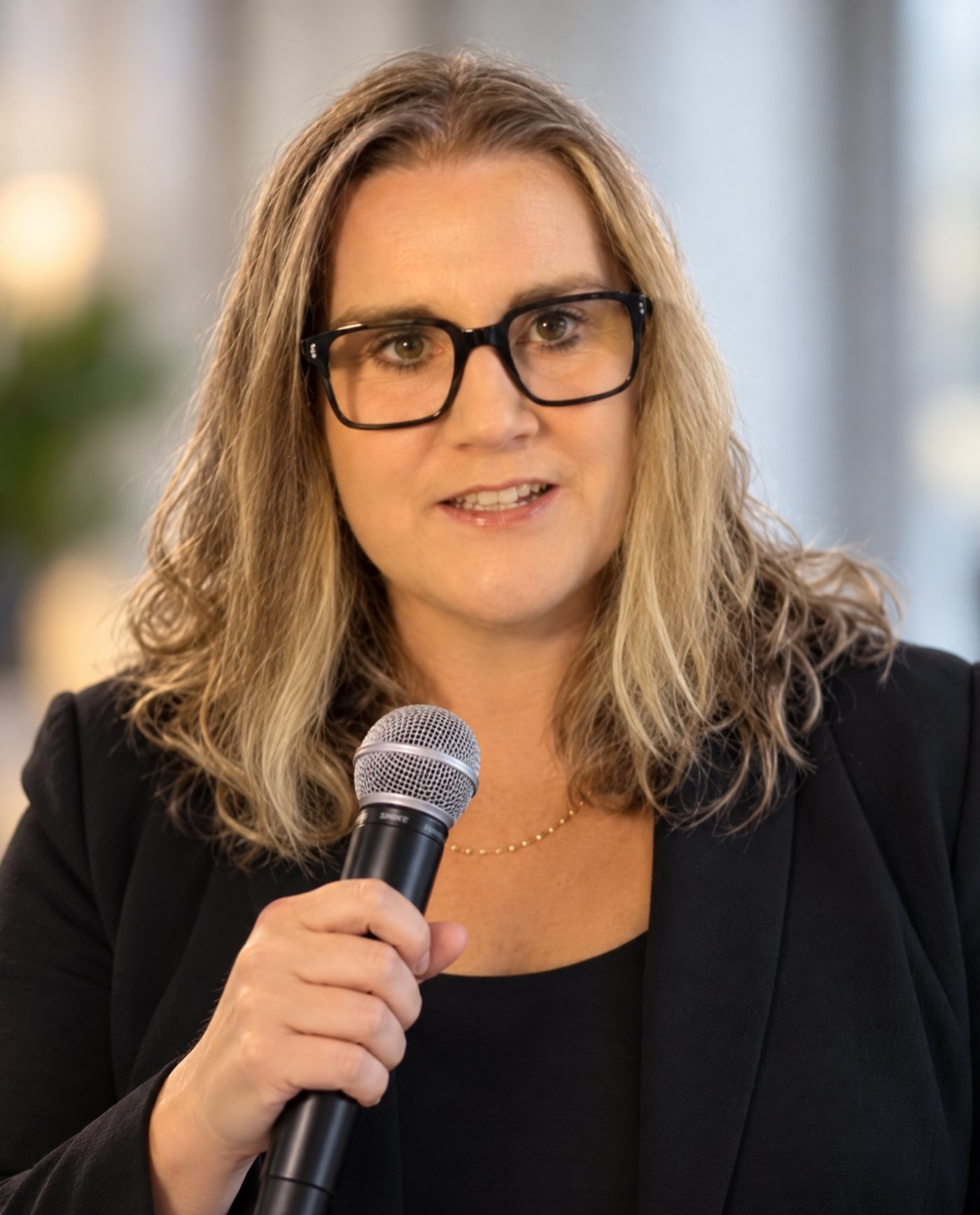 Claire Allison speaking, microphone in hand, meeting the attention in the room